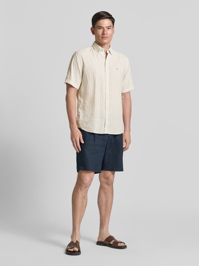 Männermodel trägt Regular Fit Freizeithemd mit Button-Down-Kragen von Fynch-Hatton, Leinen-Mix in Beige, sichtbares Logo-Stitching, Ganzkörperansicht von vorne.