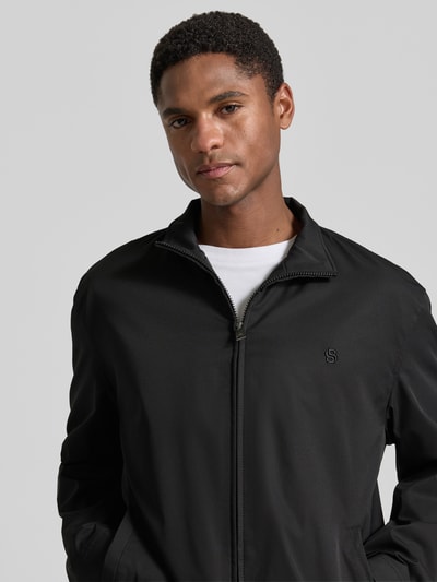 Männermodel trägt schwarzen regular fit blouson mit gestikt logo, Regular Fit Blouson mit Logo-Stitching Modell 'H-CARVO' von BOSS, heren blouson. Nahaufnahme Oberkörper.