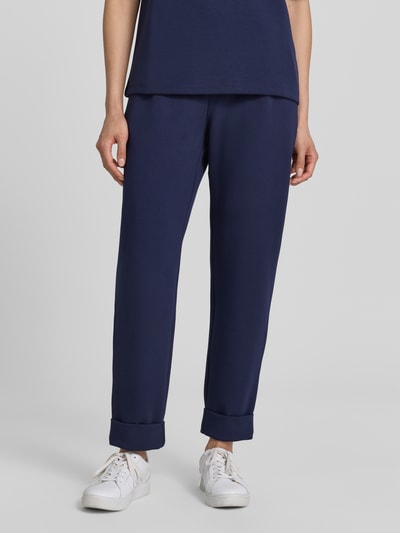 Frauenmodel trägt Straight Fit Sweatpants in verkürzter Passform von Christian Berg Woman in Dunkelblau, Elastischer-Material-Mix mit Modal-Anteil, Bundfalten, Ganzkörperansicht von vorne.