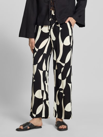Frauenmodel trägt Stoffhose aus Reine Viskose im Allover-Look Modell 'CHANISE' von Soyaconcept, Relaxed-Fit, Ganzkörperansicht von vorne. Damen Stoffhose, Bundweite 35 cm, Innenbeinlänge 76 cm, abstraktes Schwarz-Weiß-Muster, leichte Textur.