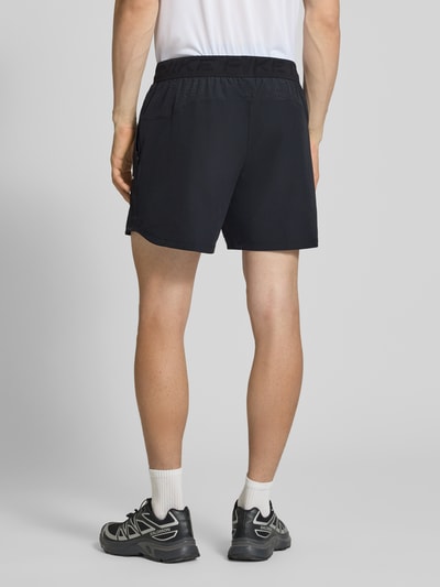 Männermodel trägt Shorts mit Logo und elastischem Bund von NIKE TRAINING in Schwarz, Regular Fit, Material-Mix mit Stretch, Ganzkörperansicht Rückansicht.