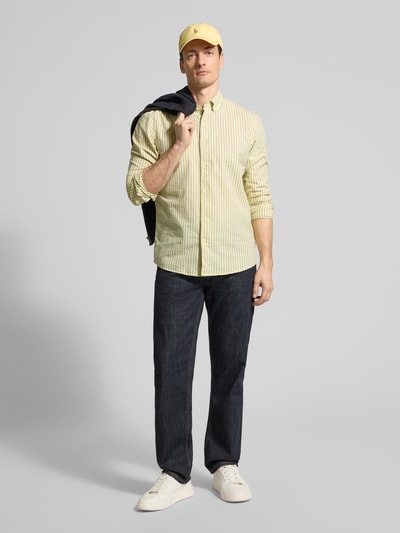 Männermodel trägt Slim Fit Freizeithemd aus reiner Baumwolle von MCNEAL mit gelb-weißen Streifen, Button-Down-Kragen, Ganzkörperansicht von vorne.