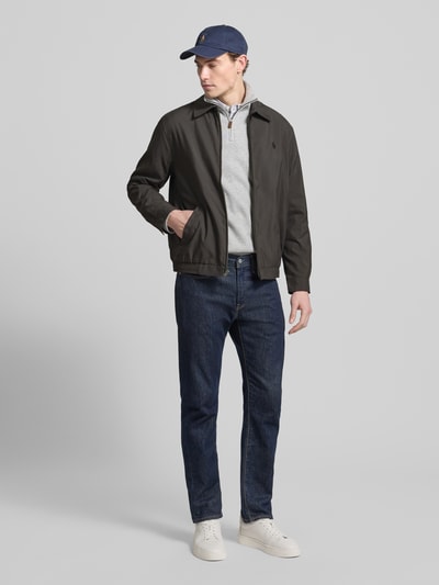 Męski model nosi Kurtka mit Label-Stitching von Polo Ralph Lauren, krój regular fit, kołnierzyk typu kent, zamek błyskawiczny, wpuszczane kieszenie, długość tyłu w rozmiarze M: 68 cm, szerokość ramion w rozmiarze M: 49 cm, szerokość klatki piersiowej w rozmiarze M: 62 cm, długość rękawów w rozmiarze M: 64 cm, ciemne odcienie, proste formy, gładka tekstura, ganzkörperansicht von vorne.