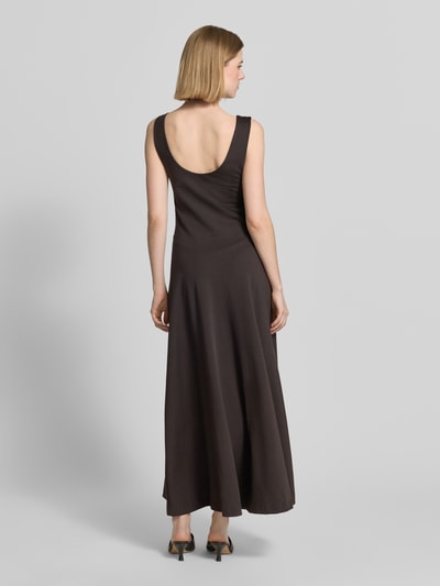 Frauenmodel trägt Maxikleid mit tiefem Rückenausschnitt Modell 'KLEALI' von Drykorn aus Lyocell-Mix mit Stretch-Anteil, taillierter Schnitt, V-Ausschnitt, breite Träger, Farbe dunkelbraun, glatte Textur, Ganzkörperansicht Rückansicht.