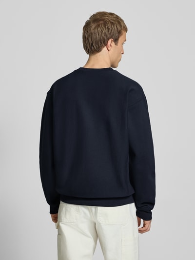 Männermodel trägt Regular Fit Sweatshirt mit Logo-Stitching von Carhartt Work In Progress aus Baumwoll-Mix, Ganzkörperansicht Rückansicht.