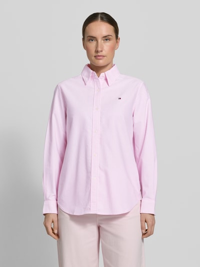 Kobiece modelka nosi Relaxed Fit Hemdbluse aus reiner Baumwolle od Tommy Hilfiger, efekt: jednolity kolor, krój relaxed fit, kołnierzyk koszulowy, detal z logo, pas na plecach, listwa guzikowa, długi rękaw, zakończenie: mankiet, wykończenie: zaokrąglony, wykończenie materiału: wzór oxford, materiał: bawełna, Ganzkörperansicht von vorne.