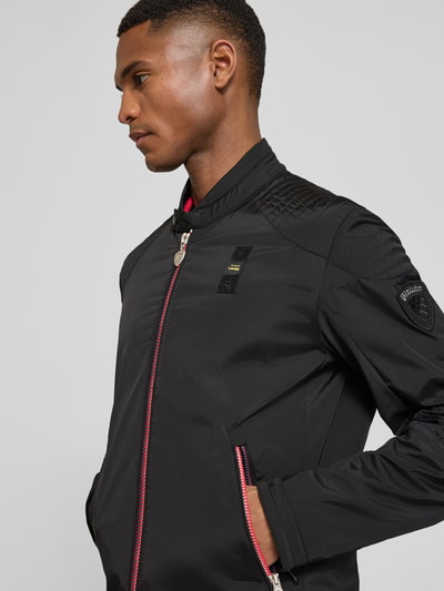 Männermodel trägt schwarze Jacke mit Zweiwege-Reißverschluss Modell 'Thayer' von Blauer Usa, Material-Mix, Nahaufnahme Oberkörper.