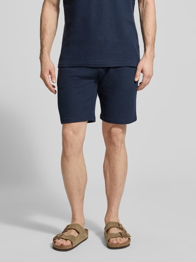 Männermodel trägt Sweatshorts mit elastischem Bund von MCNEAL in Dunkelblau, Strukturmuster, Gerade Passform, Eingriff- und Gesäßtaschen, Elastischer-Material-Mix, Ganzkörperansicht von vorne.