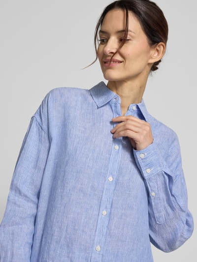 Modelka nosi bluzkę lnianą Relaxed Fit Leinenbluse mit Streifenmuster Modell 'DARIA' od ECOALF, len, krój relaxed fit, wzór w paski, kołnierzyk koszulowy, listwa guzikowa, długość tyłu w rozmiarze 36: 73 cm, długość rękawów w rozmiarze 36: 53 cm, jasnoniebieskie paski, miękka tekstura. Zbliżenie na górną część ciała.