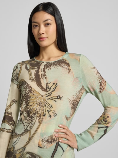 Frauenmodel trägt Slim Fit Longsleeve aus reiner Schurwolle von Marc Cain mit Allover-Animal-Print, grün-beige Töne, Nahaufnahme Oberkörper.