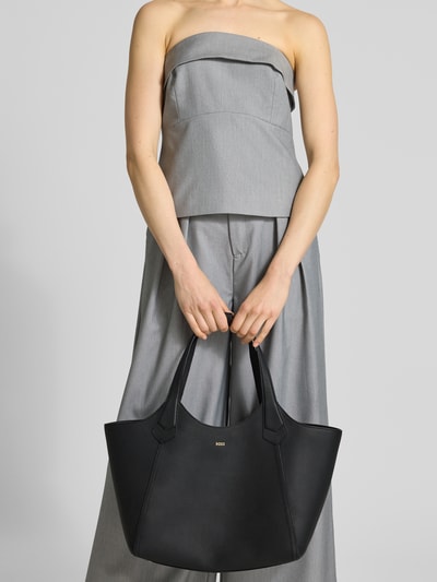 Frauenmodel trägt Shopper mit Label-Schriftzug Modell 'LENAH NEW' von BOSS in Lederoptik, echtes Leder, Ganzkörperansicht von vorne.