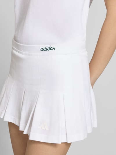 Kobiece modelka nosi Regular Fit Sportrock mit Logo-Stitching Modell 'Ski' od adidas Sportswear, biała bawełna, krój regular fit, logo, plisy, zintegrowane szorty, Szerokość w rozmiarze S: 37 cm, długość całkowita: 29 cm, zdjęcie z przodu, zbliżenie na biodra.