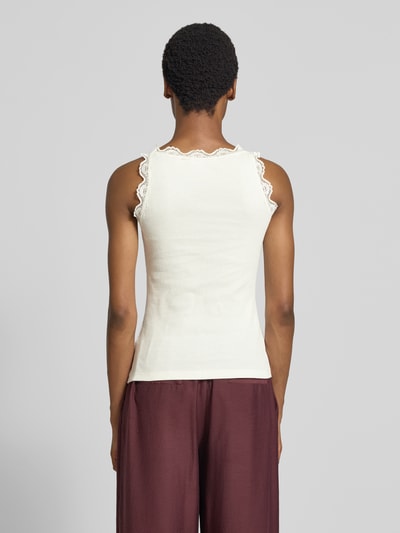 Vrouwenmodel draagt Slim Fit Top met Spitzenbesatz aus reiner Baumwolle van Rich & Royal in gebroken wit, met kant aan de randen, ruglengte maat S 56 cm, Ganzkörperansicht Rückansicht.