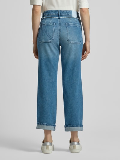 Männermodel trägt Straight Fit Jeans mit fixierten Beinabschlüssen von Marc Cain, niebieski dżins, bawełniany materiał, krój straight fit, tylne i boczne kieszenie, szerokość w rozmiarze 36: 39 cm, długość nogawki wewnętrznej: 71 cm, widok całej sylwetki z tyłu.