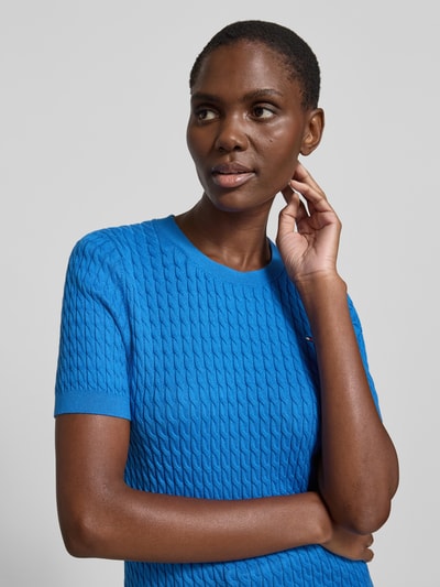 Vrouwenmodel draagt Slim Fit T-shirt uit puur katoen van Tommy Hilfiger, look: effen, kabelpatroon, logodetail, ronde hals, korte mouw, geribde mouwboord en rompzoom, knitwear, materiaal: puur katoen. Close-up bovenlichaam.