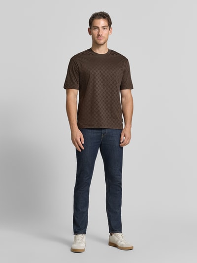 Männermodel trägt Regular Fit T-Shirt aus reiner Baumwolle Modell 'Varo' von JOOP! COLLECTION, braun gemustert, Ganzkörperansicht von vorne.