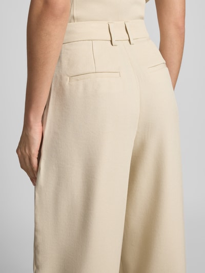 Vrouwenmodel draagt Wide Leg Pants met biezen model 'Esteriane' van MSCH Copenhagen in crèmekleurige viscosemix, detailopname rug, Franse steekzakken en paspelzakken achter, uitgewaaierd silhouet.