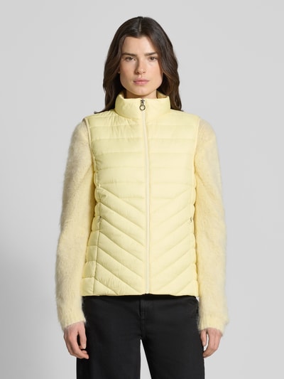 Frauenmodel trägt Regular Fit Steppweste mit Reißverschlusstaschen von s.Oliver RED LABEL in Hellgelb, unifarben, Stehkragen, Ganzkörperansicht von vorne.