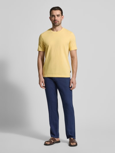 Männermodel trägt T-shirt met labeldetail van bugatti in geel, puur katoen, recht model, ronde hals, ruglengte maat M 69 cm, Ganzkörperansicht von vorne.