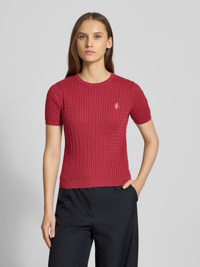 Frauenmodel trägt Kurzarmpullover mit Zopfmuster und Rundhalsausschnitt von Review aus reiner Baumwolle, Slim-Fit, Logo, Rippbündchen; Nahaufnahme Oberkörper.