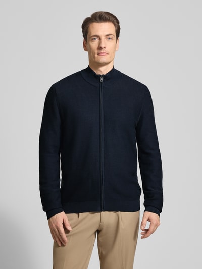 Męski model nosi Regular Fit Cardigan mit Stehkragen von OLYMP Level Five z bawełny, imitacja dzianiny, zamek błyskawiczny, elastyczne wykończenia, długość tyłu 68 cm, długość rękawów 67 cm, krój regular fit, widok całej sylwetki z przodu.
