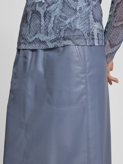 Frauenmodel trägt Midirock in Leder-Optik mit Eingrifftaschen von Marc Cain, straight Fit, elastischer Bund, Detailaufnahme Rückansicht.