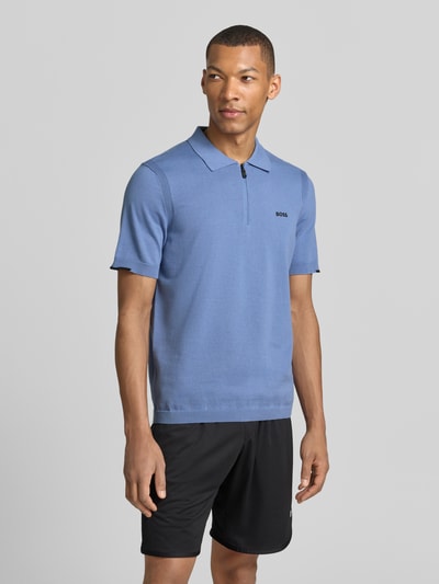 Männermodel trägt Regular Fit Poloshirt aus reiner Baumwolle Modell 'KN_EVER-X' von BOSS Green in Blau mit Label-Applikation, Feinstrick, Polokragen und kurzem Reißverschluss, Optik: Unifarben, Kurzarm, Ganzkörperansicht von vorne.