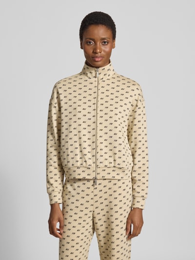 Frauenmodel trägt Sweatjacke mit Reißverschluss von Armani Exchange, cremefarben mit Allover-Label-Print, lockere Passform, Ganzkörperansicht von vorne.