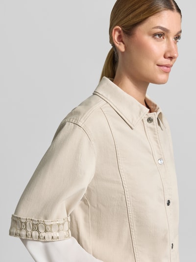 Frauenmodel trägt Relaxed Fit Blazer aus Baumwoll-Mix in Denim-Optik von Marc Cain, beige, strukturierte Oberfläche, Halbarm, Umlegekragen, Knopfleiste, Nahaufnahme Oberkörper.