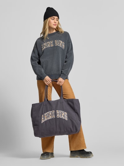 Vrouwenmodel draagt Tote Bag uit canvas van Anine Bing, grijze kleur, open hoofdvak, smalle schouderbanden, labelstitching, siernaden, maat 1: breedte 50 cm, lengte 39 cm, diepte 16 cm, canvasstructuur, vooraanzicht van het volledige lichaam