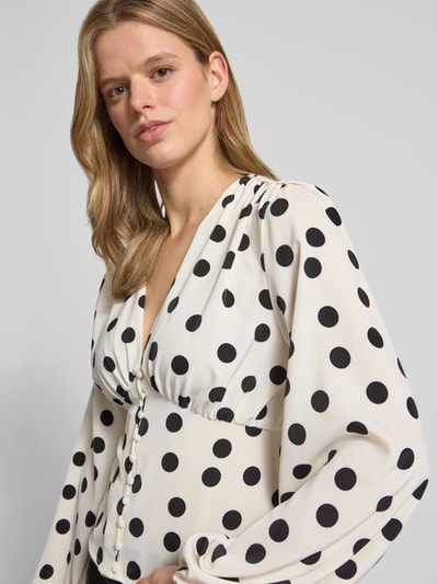 Vrouwenmodel draagt blouse met lange mouwen met sjaalkraag, sierknoopsluiting, getailleerde pasvorm, ballonmouwen van Gina Tricot, ruglengte maat 36: 49 cm, mouwlengte maat 36: 64 cm, effen wit met zwarte stippen, structuur glad, Nahaufnahme bovenlichaam