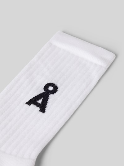 Produktfoto, Socken aus Baumwoll-Mix Modell 'SAAMUS BOLD' von Armedangels, Optik: Unifarben, Applikation: Label-Schriftzug, Logo-Detail, Bundabschluss: Gerippt, Materialverarbeitung: Stretch, weiße Struktur mit schwarzem Logo auf glatter, leicht gerippter Oberfläche.