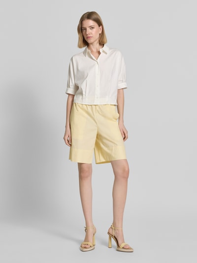 Frauenmodel trägt Straight Fit Shorts mit elastischem Bund von Rich & Royal aus Reine Baumwolle in Gelb, Knielänge, Ganzkörperansicht von vorne. Bundweite bei Größe S: 35 cm, Innenbeinlänge bei Größe S: 24 cm.