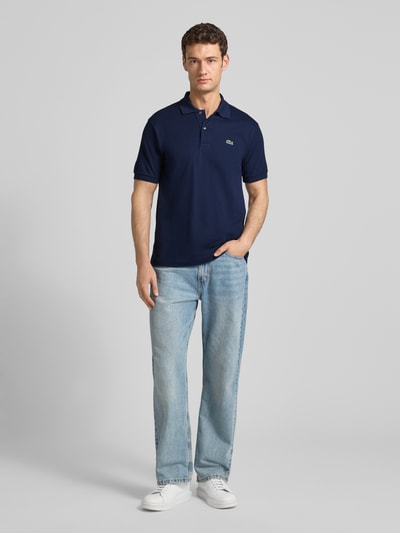 Männermodel trägt Poloshirt mit Label-Stitching Modell 'L.12.12 CORE' von LACOSTE in Unifarben, aus reiner Baumwolle, Regular-Fit, Ganzkörperansicht von vorne.