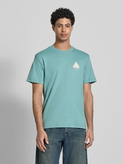 Männermodel trägt Regular Fit T-Shirt mit Logo-Detail von G-Star Raw aus reiner Baumwolle in Türkis, Rundhalsausschnitt, Ganzkörperansicht von vorne. Rückenlänge bei Größe M: 70 cm.