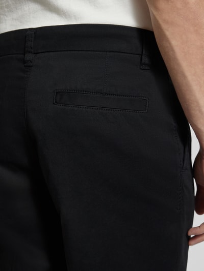 Männermodel trägt Regular Fit Chino aus Baumwoll-Mix Modell 'TAAMIR PLEATED' von Armedangels, efekt: jednolity kolor, wyhaftowane logo, kieszeń z tyłu, mieszanka bawełny, detalaufnahme.