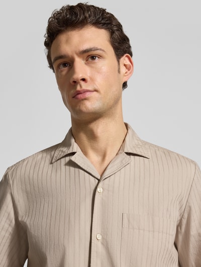 Männermodel trägt Regular Fit Freizeithemd aus reiner Baumwolle Modell 'RAYER_M' von BOSS Orange in Beige mit Streifenmuster, Nahaufnahme Oberkörper.