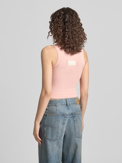 Frauenmodel trägt Slim Fit Top mit Logo-Detail von ANOTHER COTTON LAB in Hellrosa, elastischer Baumwoll-Mix, Rundhalsausschnitt, Ganzkörperansicht Rückansicht