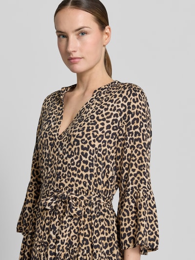 Vrouwenmodel draagt Tailliertes Tunikakleid aus reiner Viskose Modell 'MELBA' van Vero Moda in allover panterprint, getailleerde fit, mini-lengte, V-hals, met riemlussen, bindriem, trompetmouwen en volantzoom van pure viscose, close-up bovenlichaam.