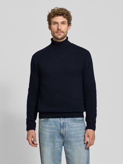 Männermodel trägt Slim Fit Rollkragenpullover aus Woll-Mix Modell 'Karl' von Casual Friday, dunkelblau, gerippte Abschlüsse, Ganzkörperansicht von vorne.