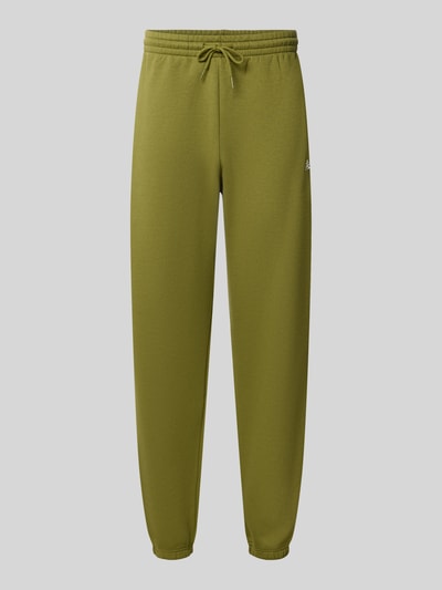 Produktfoto, Regular Fit Sweatpants aus Baumwoll-Mix mit Label-Stitching von New Balance in Olivgrün, elastischer Bund und Tunnelzug, glatte Oberfläche, Herren Sweatpants, Innenbeinlänge 79 cm, schlichte Form.