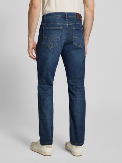Männermodel trägt Modern Fit Jeans Modell 'Fortress' von JOOP! Collection, Baumwoll-Elasthan-Mix, blaue Denimtextur, Ganzkörperansicht Rückansicht.