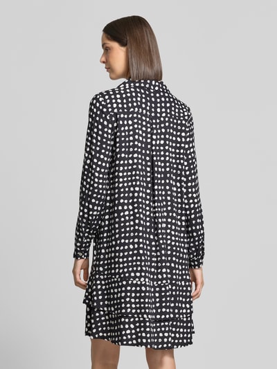 Frauenmodel trägt Knielanges Kleid aus reiner Viskose von Emily Van den Bergh, schwarz mit weißen Punkten, Relaxed Fit, Umlegekragen, langärmelig, Rückenansicht, Ganzkörperansicht.
