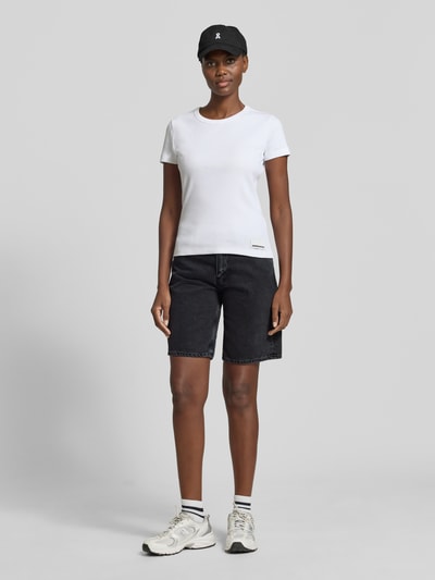 Vrouwenmodel draagt Regular Fit Jeansshorts uit puur katoen model 'THALINAA' van Armedangels met denimlook, 5-pocketmodel, labelpatch, twill, knoop- en ritssluiting, riemlussen, zwarte kleur, materiaalverwerking: puur katoen, volledige lichaamsaanzicht van voren.