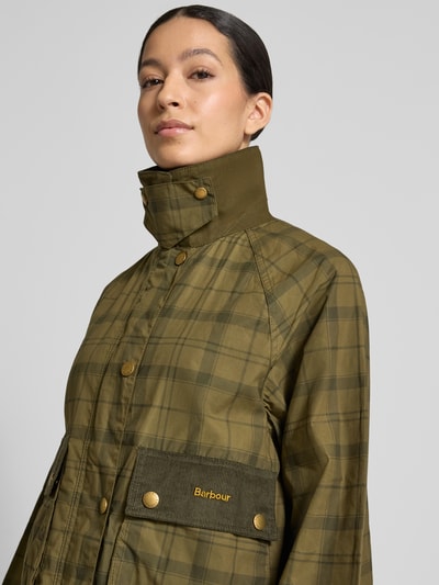 Kobiece modelka nosi Regular Fit Funktionsjacke aus reiner Baumwolle Modell 'BEADNELL' od Barbour, tartanowy wzór, oliwkowa zieleń, złote guziki, materiał bawełniany, funkcja wodoodporna, widok z przodu, zbliżenie na górną część ciała.