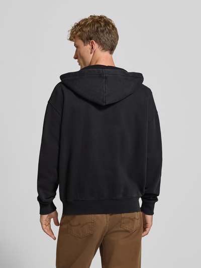 Männermodel trägt schwarze Regular Fit Sweatjacke aus Baumwoll-Mix von PEGADOR mit Kapuze, geteilte Kängurutasche, Rückenansicht.