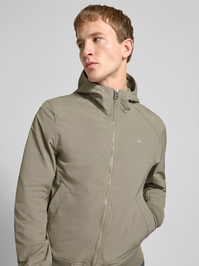 Männermodel trägt Regular Fit Jacke mit Logo-Print Modell 'Track' von G-Star Raw in Beige, Kapuze, elastische Abschlüsse, Nahaufnahme Oberkörper