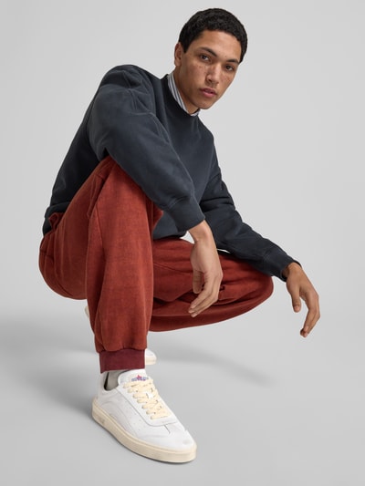 Männermodel trägt Sneaker mit Label-Detail von Dsquared2, abgerundete Spitze, Schnürverschluss, strukturierte Sohle, Ganzkörperansicht von vorne.