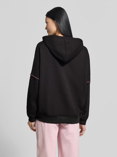 Frauenmodel trägt Hoodie aus reiner Baumwolle von miss goodlife in Schwarz mit Pailletten-Besatz, lockere Passform, elastische Abschlüsse, Ganzkörperansicht Rückansicht.