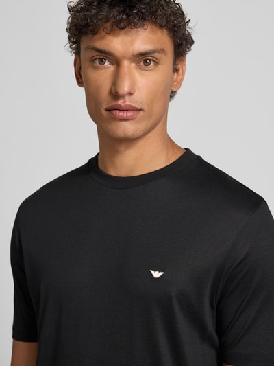 Männermodel trägt T-Shirt mit Label-Stitching von Emporio Armani, schwarz, Lyocell-Baumwoll-Mix, Regular-Fit, Nahaufnahme Oberkörper.